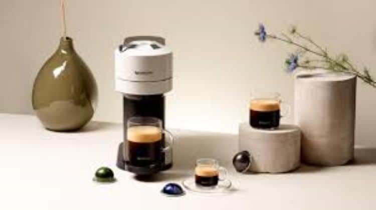 cápsulas Nespresso colocadas en fila junto a una cafetera espresso doméstica